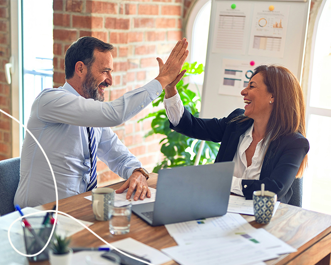 Sliderbild von einem Mann und einer Frau die im Büro sitzen und einschlagen und dazu sehr glücklich wirken dazu eine helle geschwungenen Linie unten links in der Ecke als Gestaltungselement | Kremer Signature Design