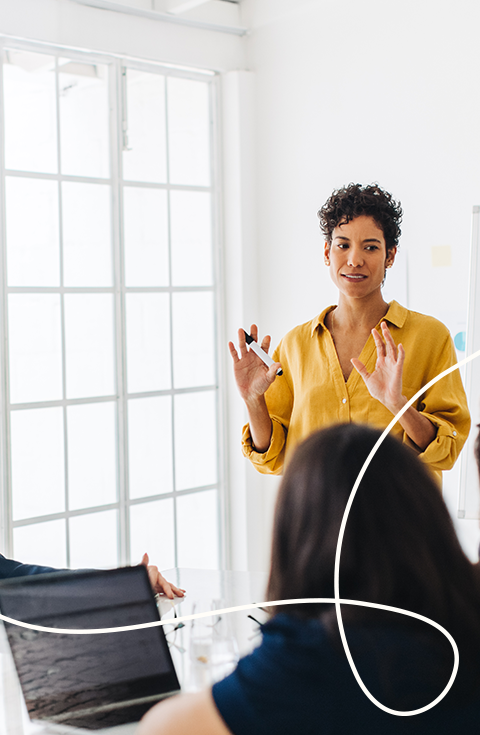 Bild einer präsentierenden Frau in gelber Bluse und in der rechten unteren Ecke befindet sich eine helle geschwungenen Linie als Gestaltungselement | Kremer Signature Design